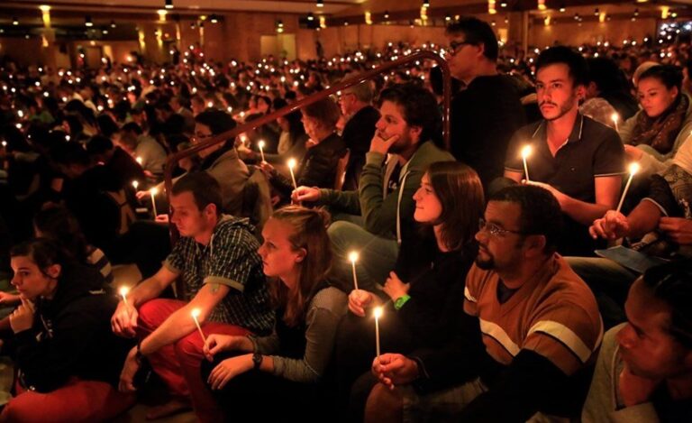 Picture of a crowd of people all holding a lit candle