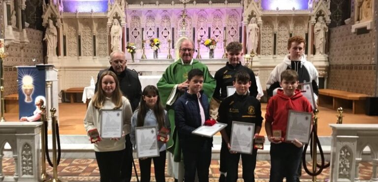 Image of alter servers receiving certificates from the priest at the alter