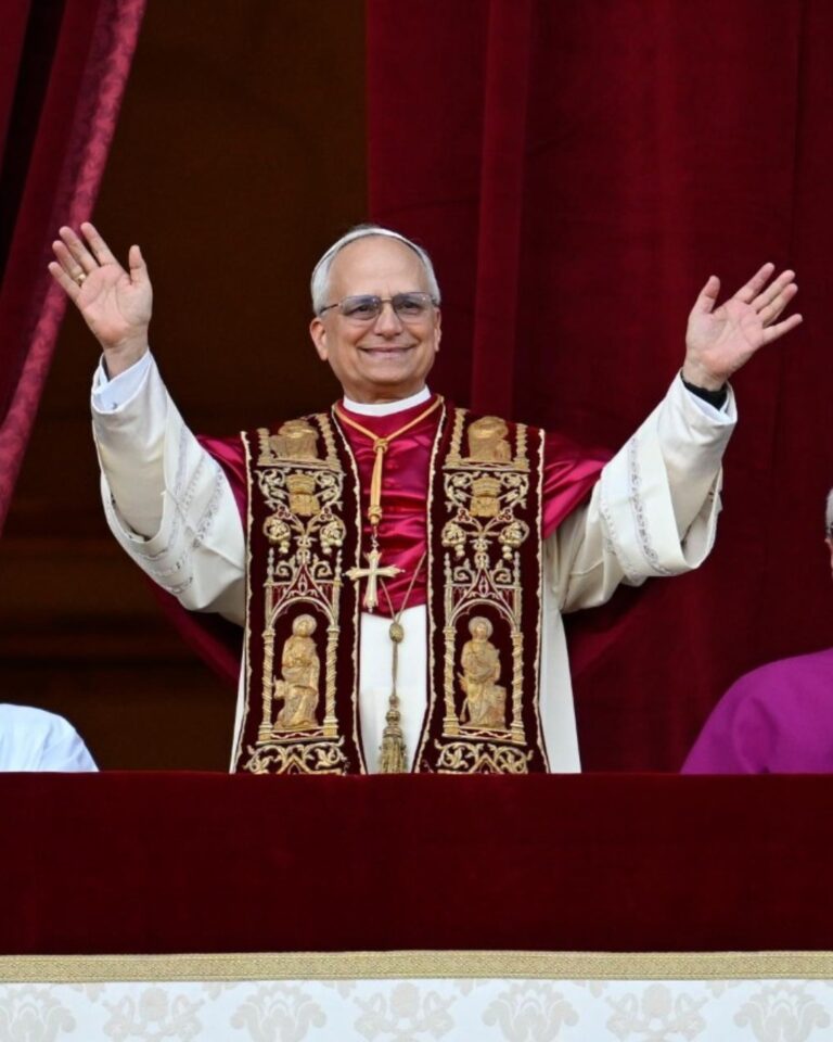 Image of Pope Leo with a red and gold sash with his arms outstretched