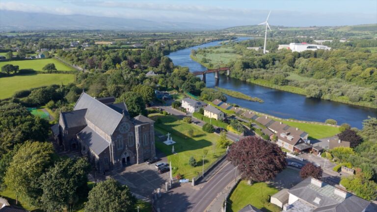 Aerial photo of a town beside a river , with a church in the foreground