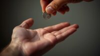 Image of a hand placing a coin into another outstretched hand.